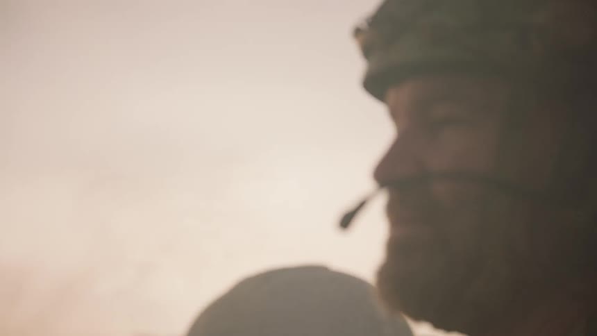 Soldiers stand outside in a smoky area at sunset