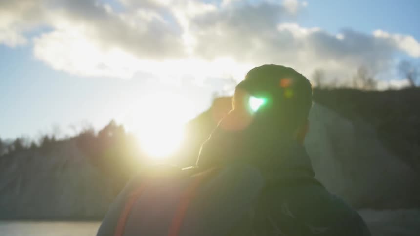 Man walking towards a large hill as the sun rises