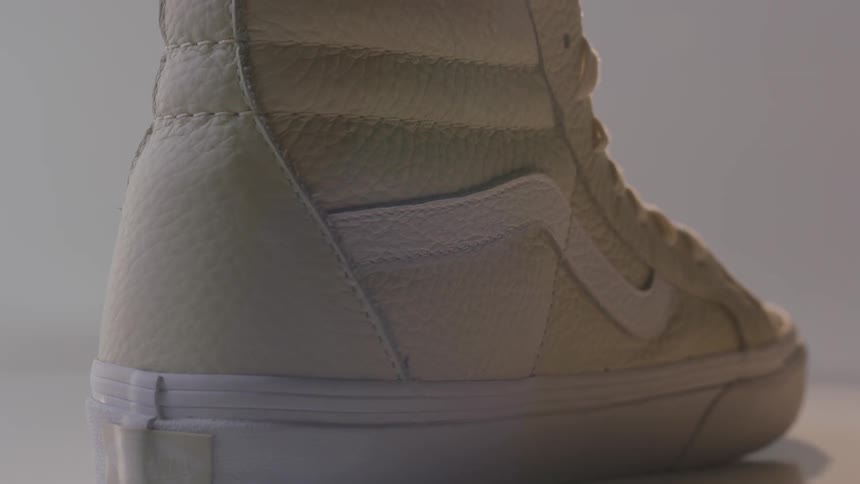 A white sneaker rotates under a light