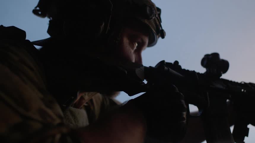 A soldier aims his gun