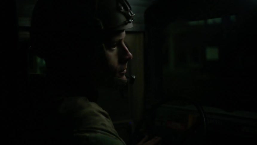A soldier looks out from a moving vehicle