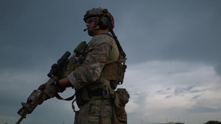 Soldiers stand on a rooftop and scan the area