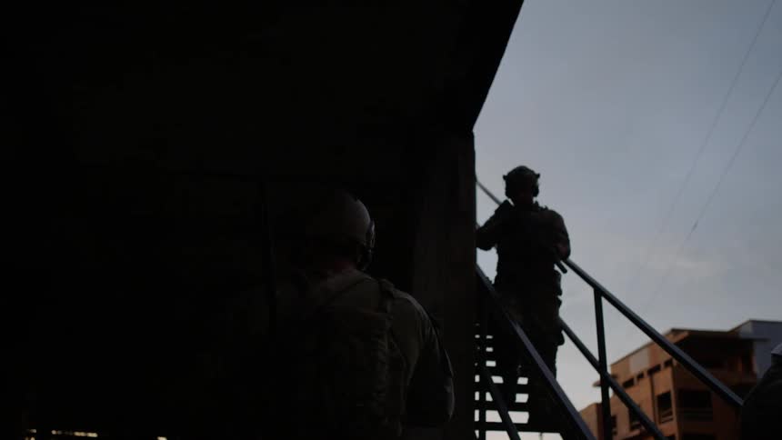 A soldier slowly moves down the stairs following others