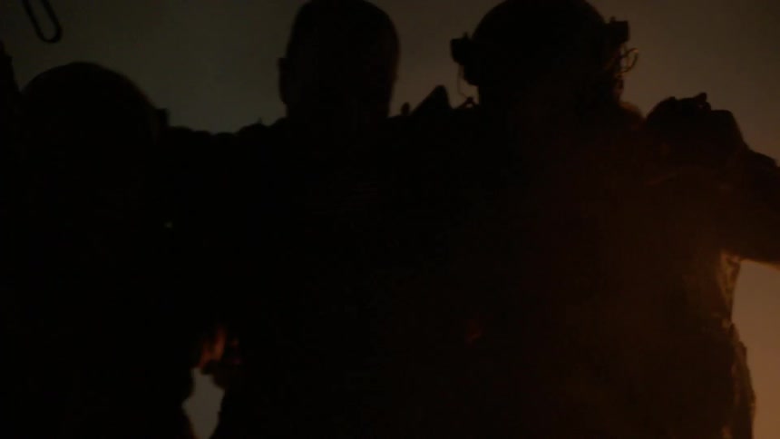 Soldiers helping another in a dark area outdoors