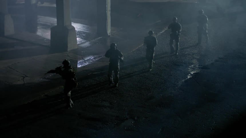 Soldiers patrol with rifles drawn in a street at night