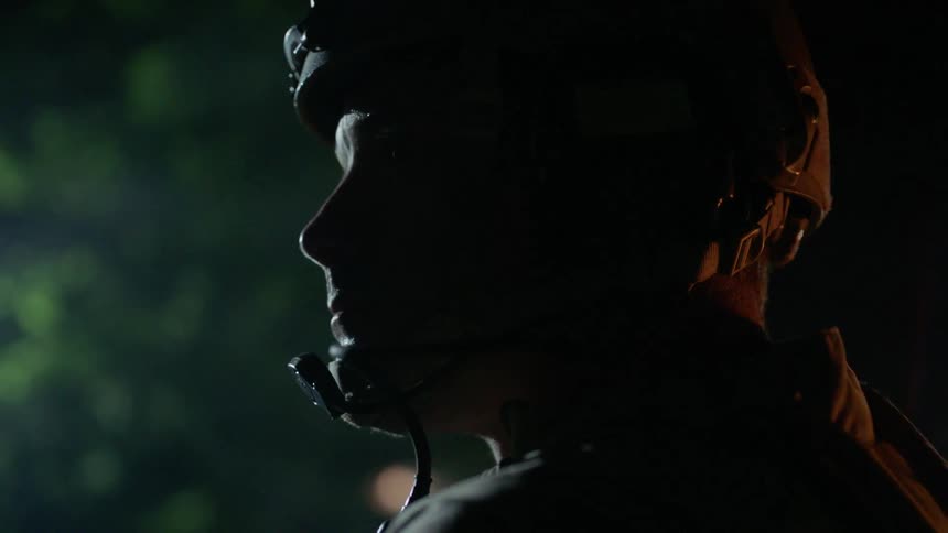 A soldier wearing a helmet and microphone turns his head