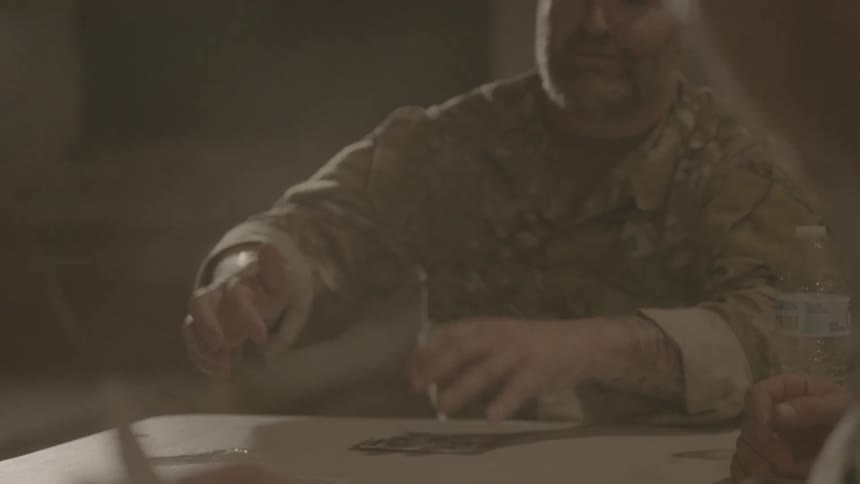 Two soldiers play cards together