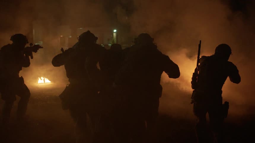 Soldiers carry a wounded soldier through a war zone
