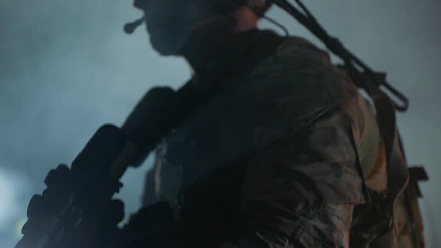 Soldier stands on a rooftop looking in the distance