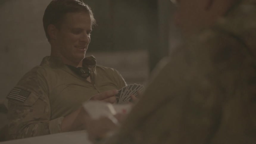 A man sits back smiling playing cards