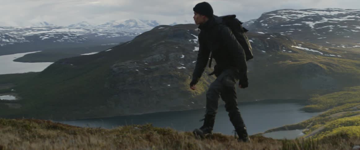 A man hikes uphill on a cloudy day