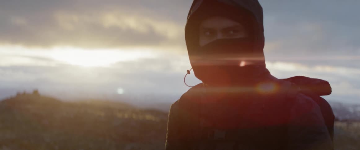 A hiker pulls the hood of his jacket of himself and walks away