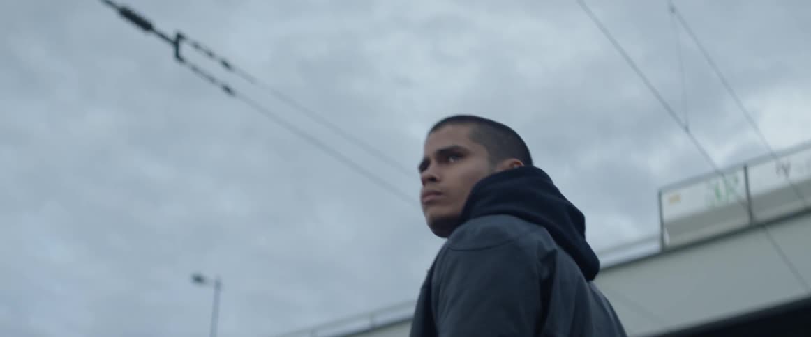 A man looks around near power lines and an overpass