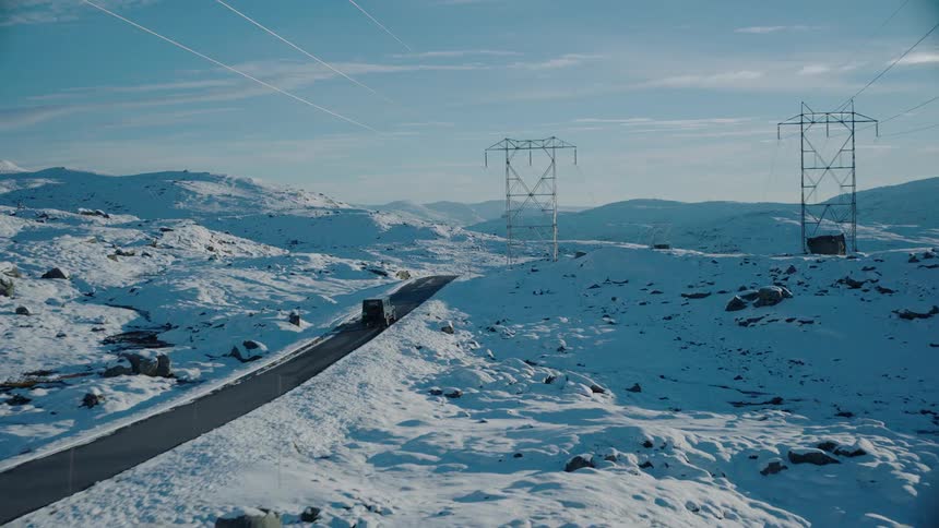 A jeep travels down a rural snowy road with power lines