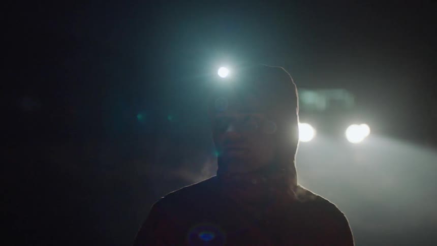 A man walks outside at night with a headlamp on