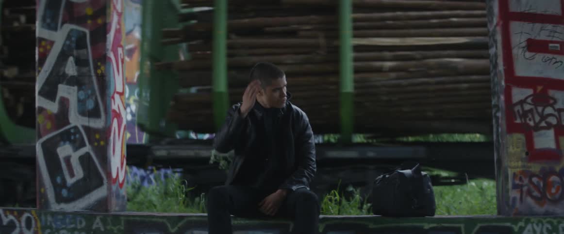 A man sits on a bench as a train passes