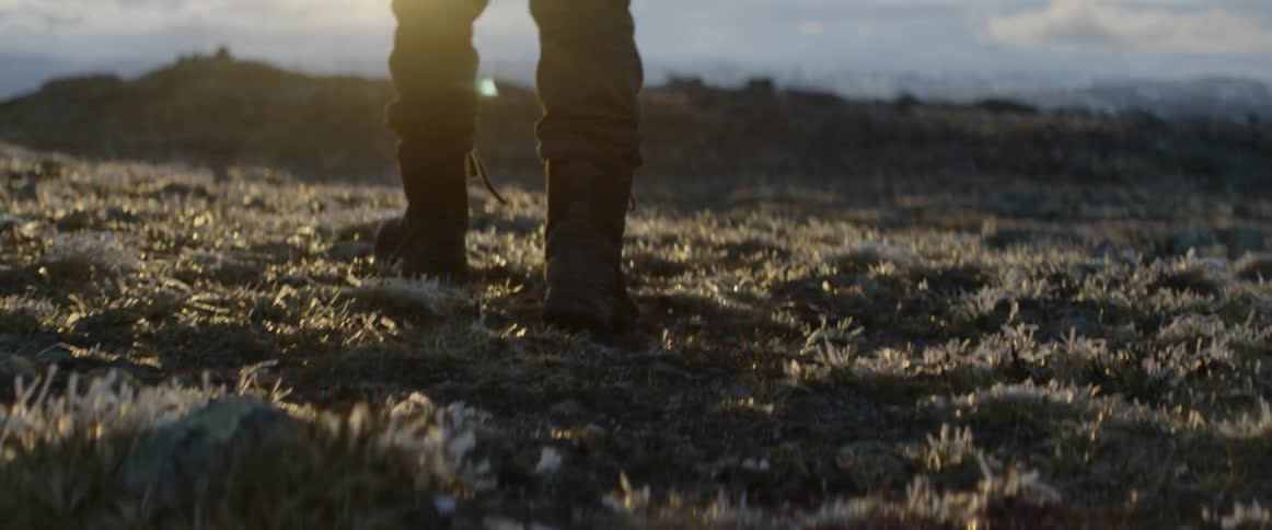 Man walks across a field at sunset