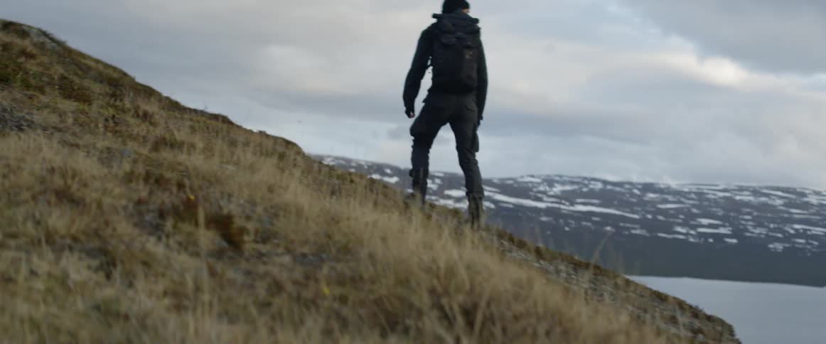 A backpacker looks back as climbs up a slope