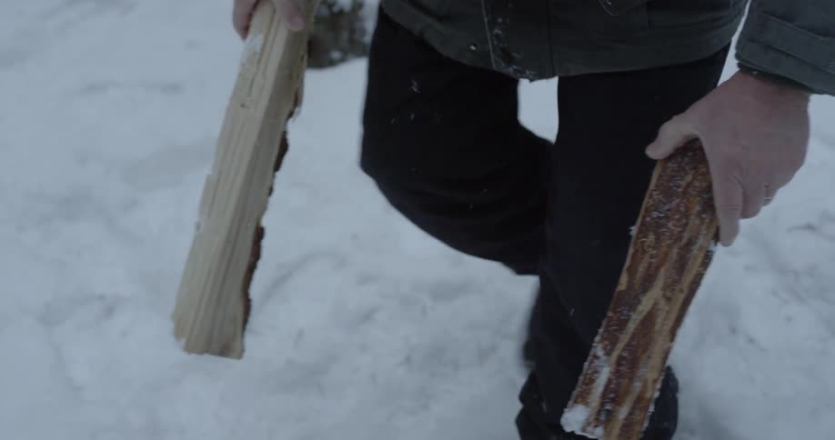 A man gathers firewood in the snow