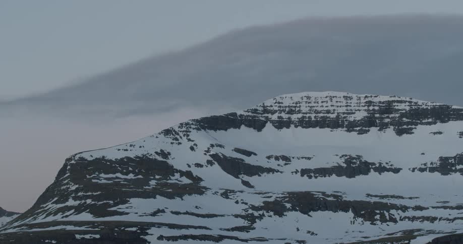 Clouds pass above snowy mountains