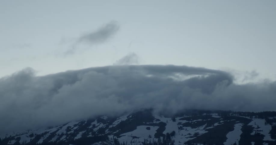 Clouds pass above a snowy mountain