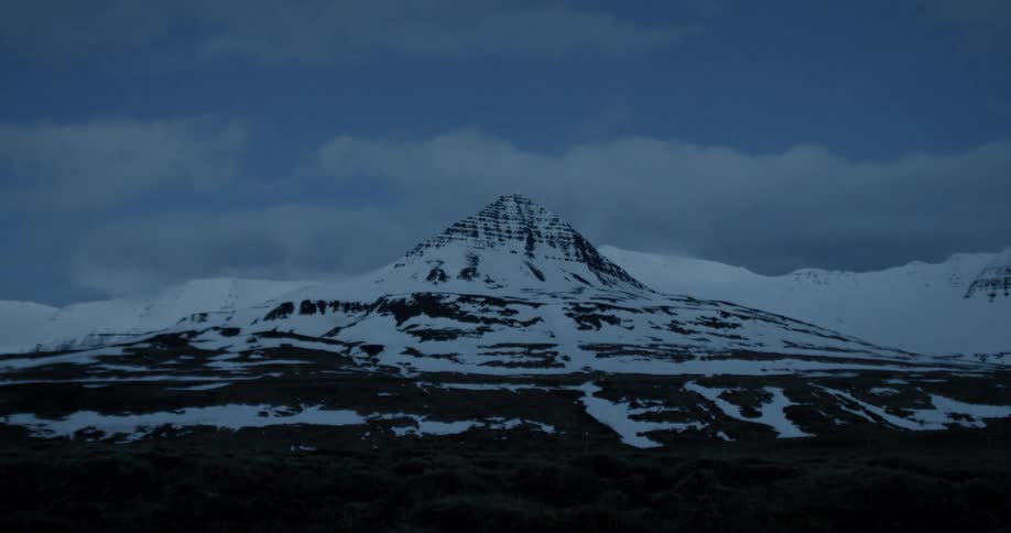 Clouds pass over a snowy mountain