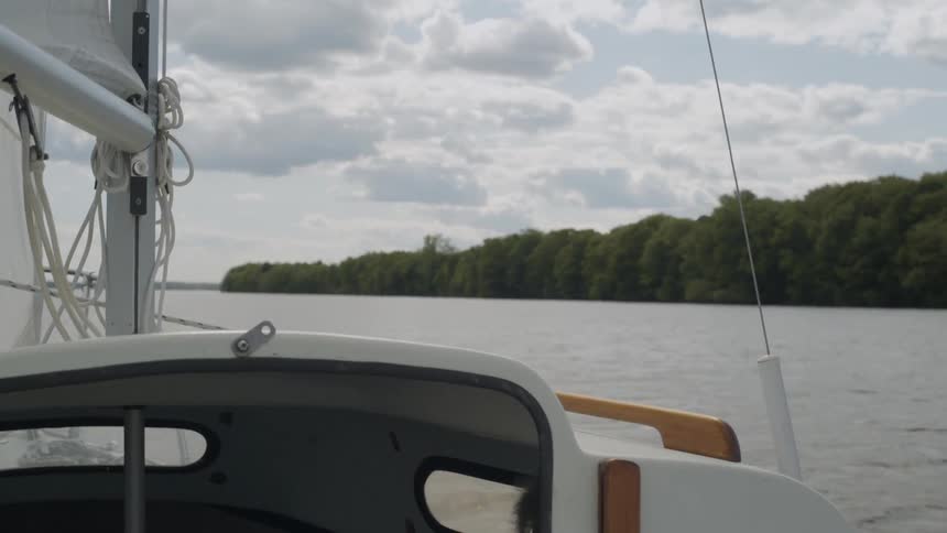 A boat moving past tree lined land