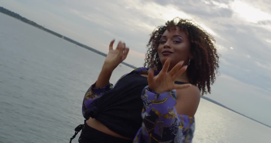 A woman dances next to a lake