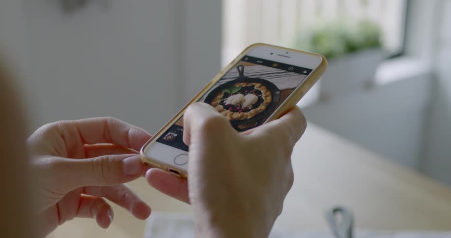 A person takes a photograph with their phone of a dish