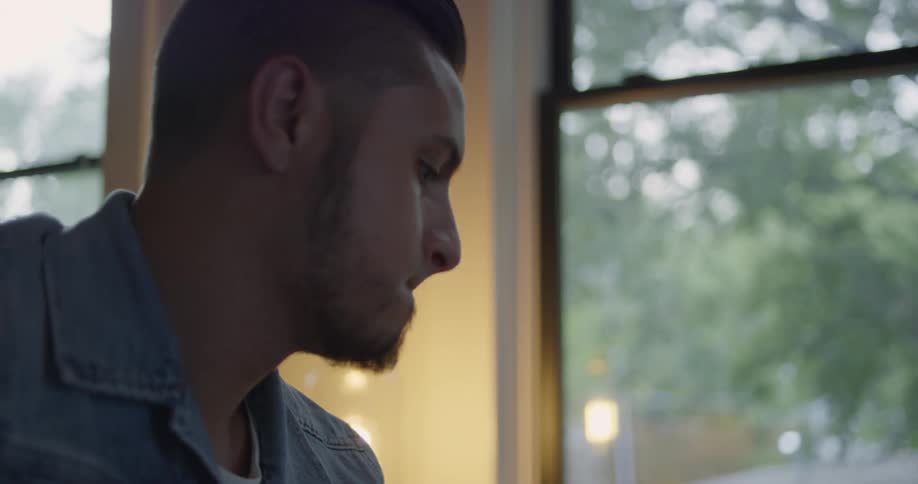 Man plays guitar while looking out a window