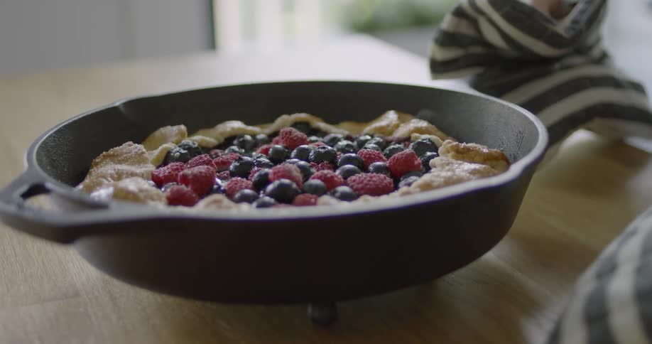 Woman places a pie in a cast iron pan on a trivet to cool off