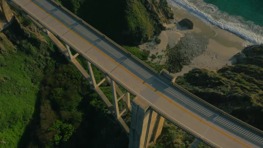 The car drives over the bridge by the shore