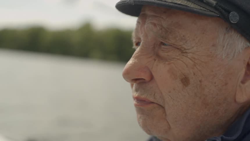 A close up view of a man sitting in a boat on a lake