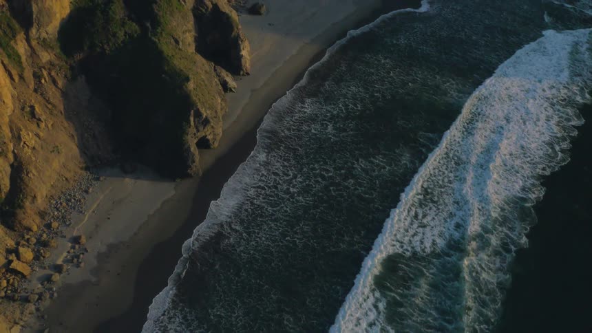 Ocean waves rolling onto beach at sunset