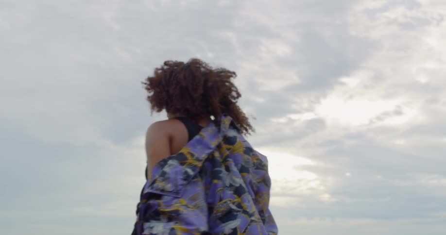 A woman is dancing outside by the water