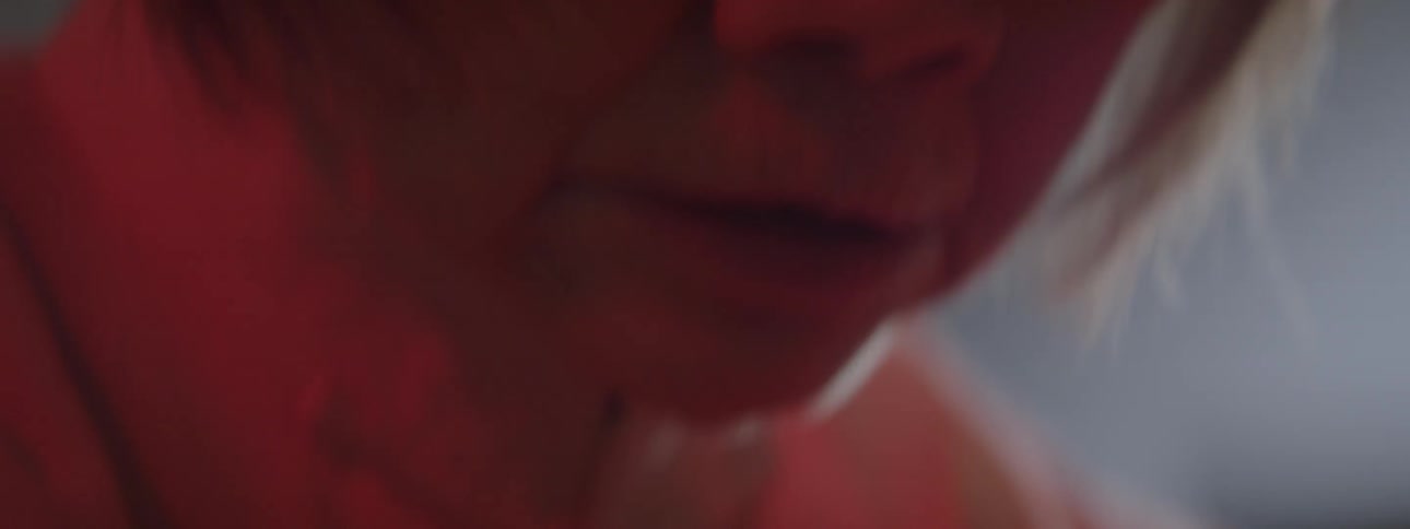 A woman is looking down worried in a dark room