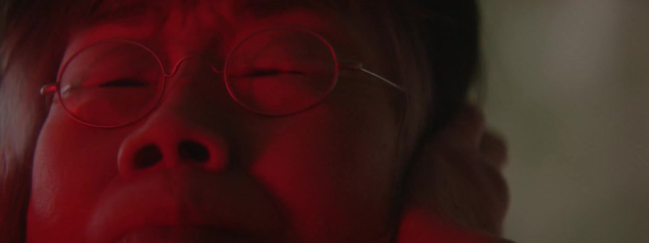 A woman wearing glasses holds her head