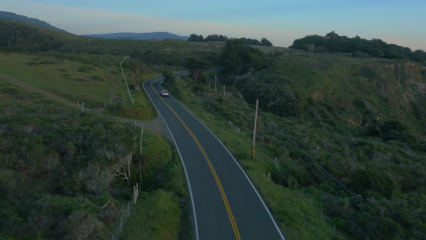 Car drives on a rural road at sunrise