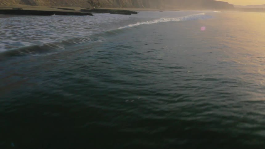 The waves crash against the shore at sunrise