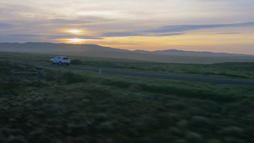 Vehicle drives on a rural road at sunset