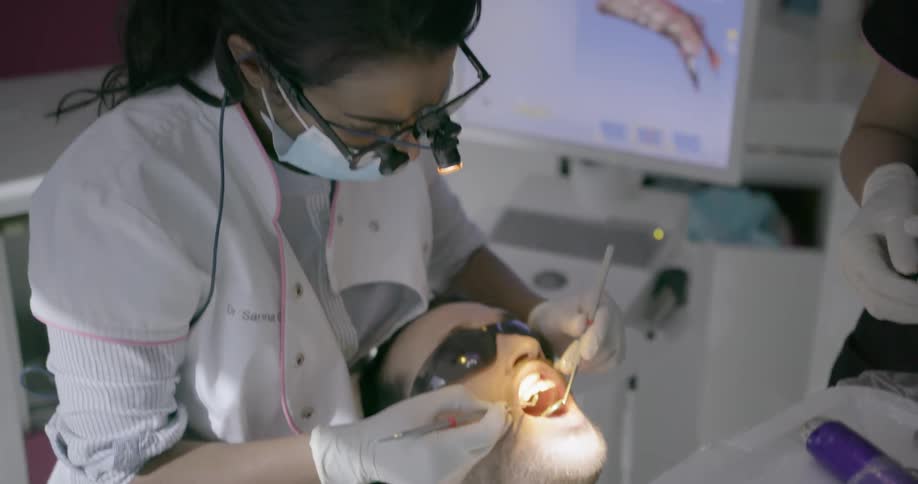 A dentist works on a patient in her office