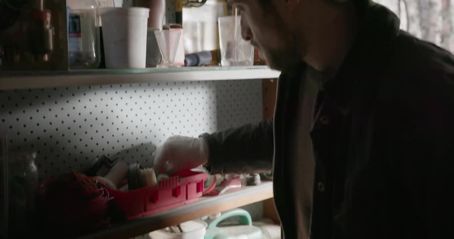 A man looks through tools on a shelf