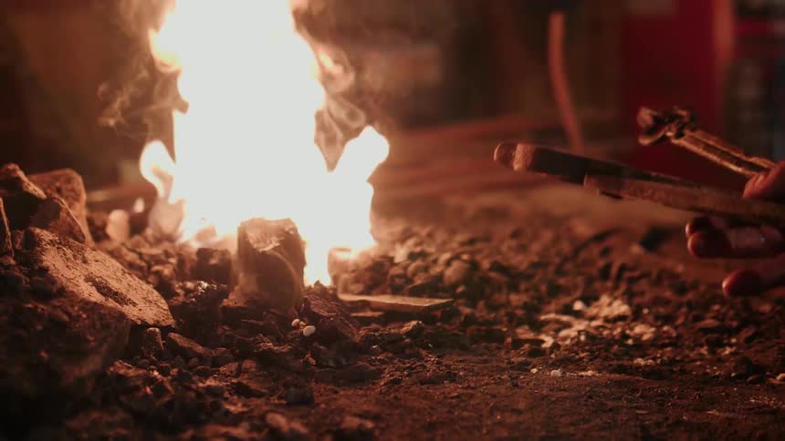 A blacksmith removes tools from a burning kiln