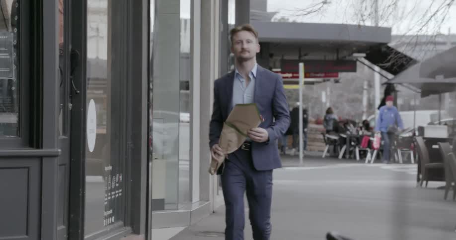 A man carrying flowers walks beside a building