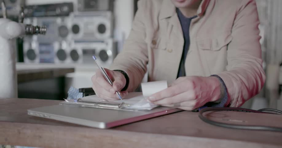 A man looks at a receipt and writes on paper
