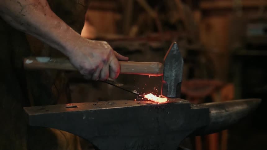 A blacksmith hammers on a glowing steel rod