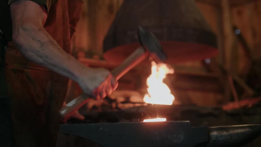 A blacksmith hammers a piece of hot metal