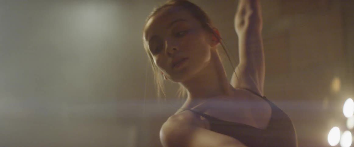 A woman dances with lights shining on her