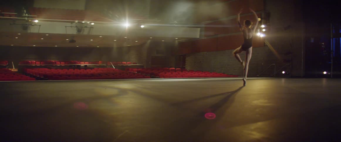 A ballerina dances on a stage in an empty theater