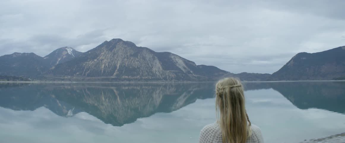 A woman is standing on the edge of a lake